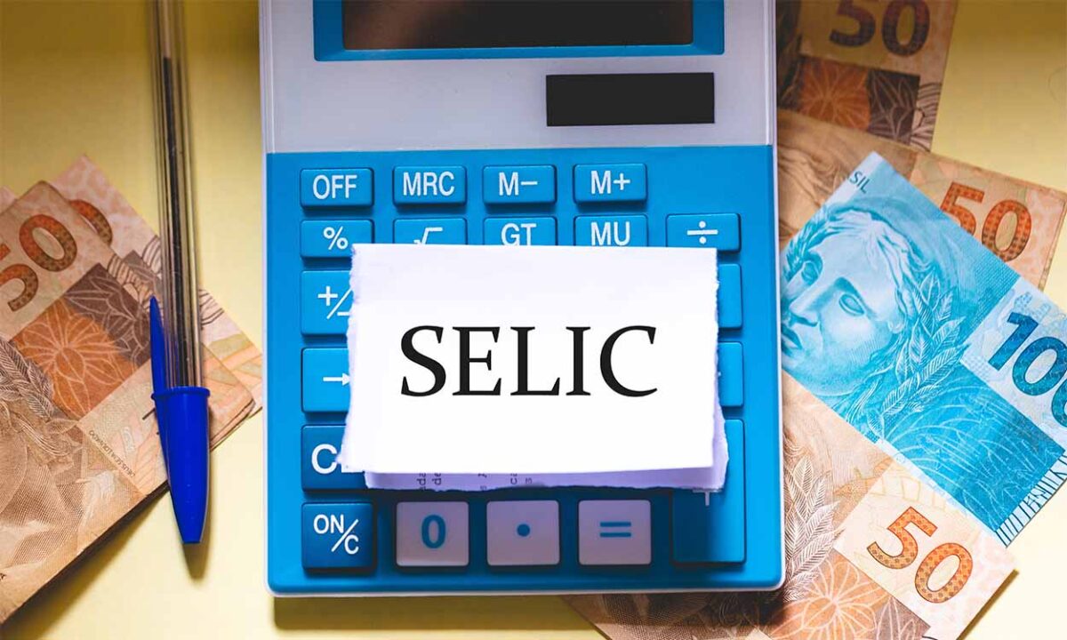 Papel escrito "selic"em cima de uma calculadora com notas de dinheiro em baixo